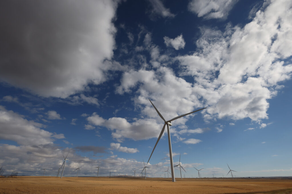 Windmills are seen on Alberta's prairie landscape, with clouds above.