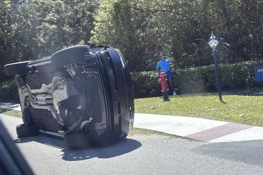Golfer Tiger Woods stands by his overturned vehicle in Florida on Friday