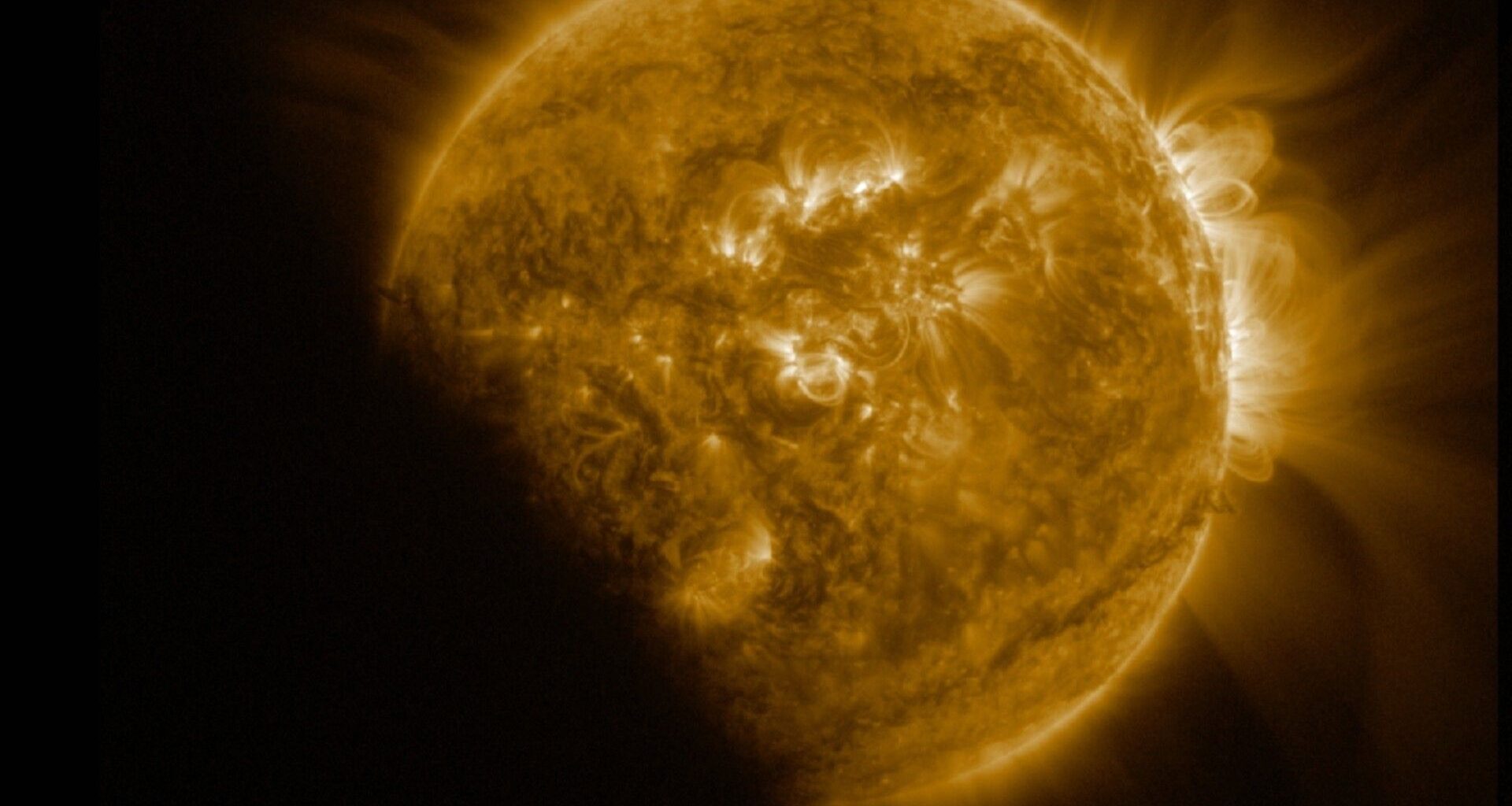 A yellow orb with loops coming out of it and hazy rays all around is slightly blocked by a shadow toward the bottom left of the screen.