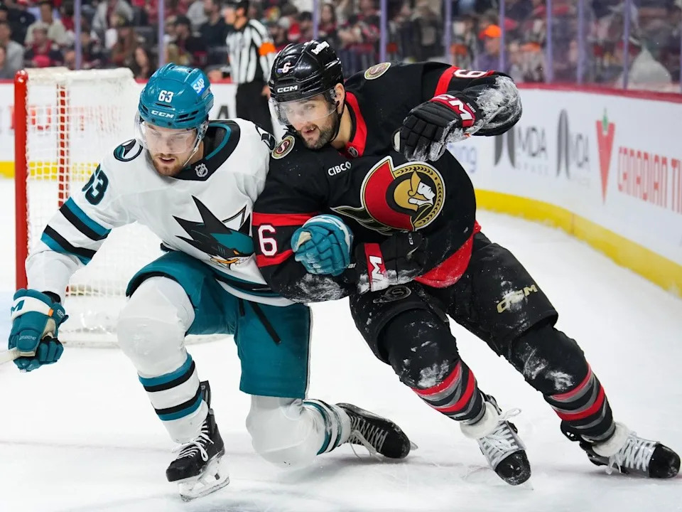  Zack Ostapchuk of the San Jose Sharks battles with Dennis Gilbert of the Ottawa Senators in the first period at Canadian Tire Centre on March 15, 2026.
