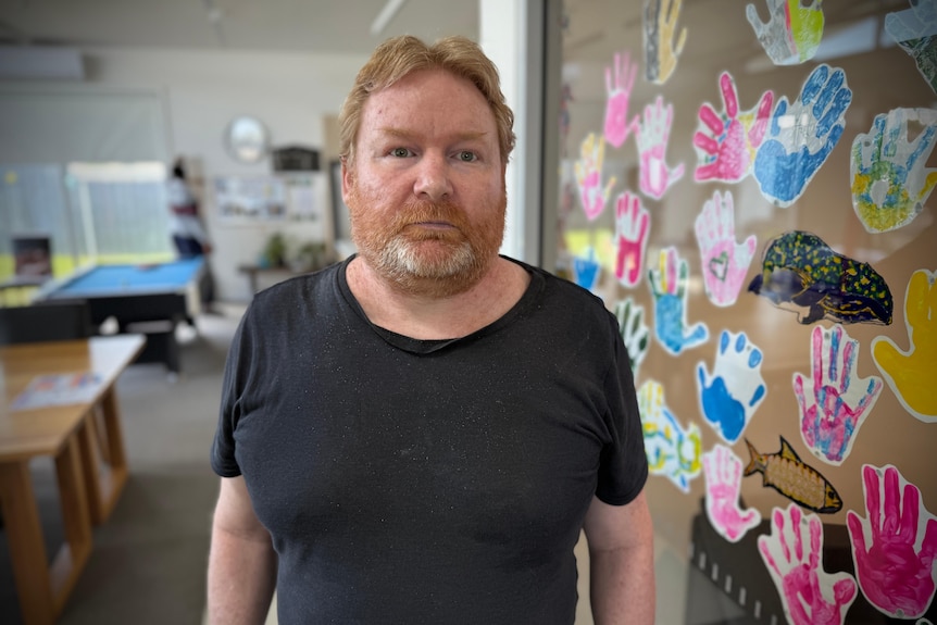 A middle-aged man, Darren Benson, stands in a communal area of a supported housing facility.