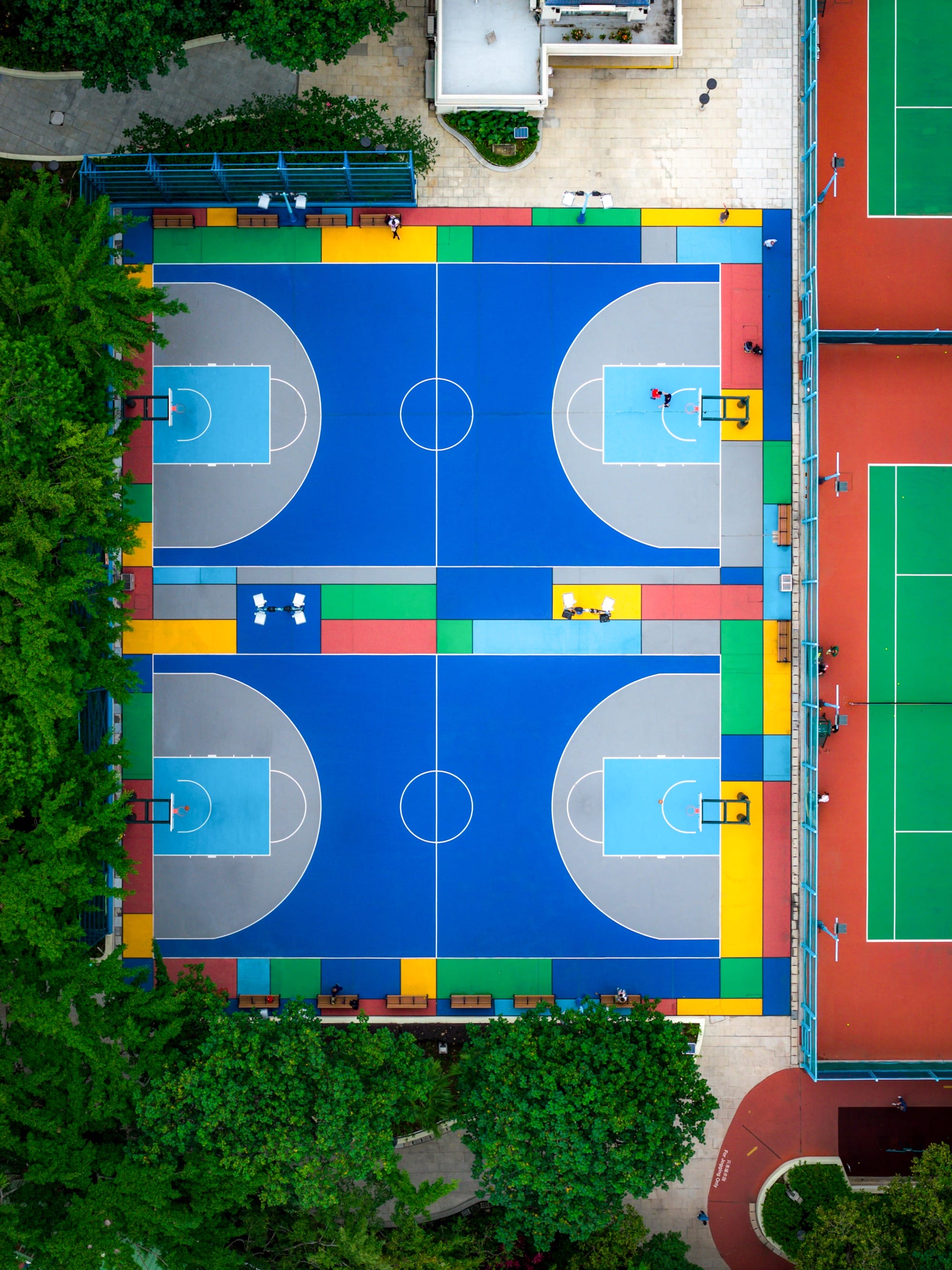 An aerial view of two colorful basketball courts amid tall buildings in Hong Kong