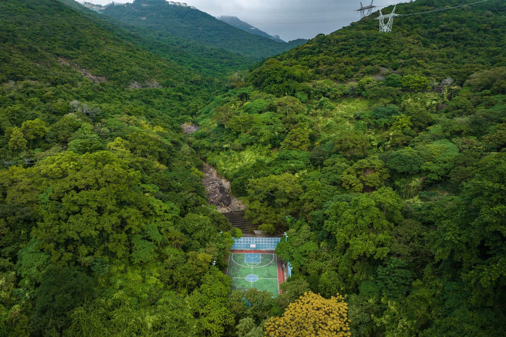 A colorful basketball court in a wooded, mountainous area near Hong Kong