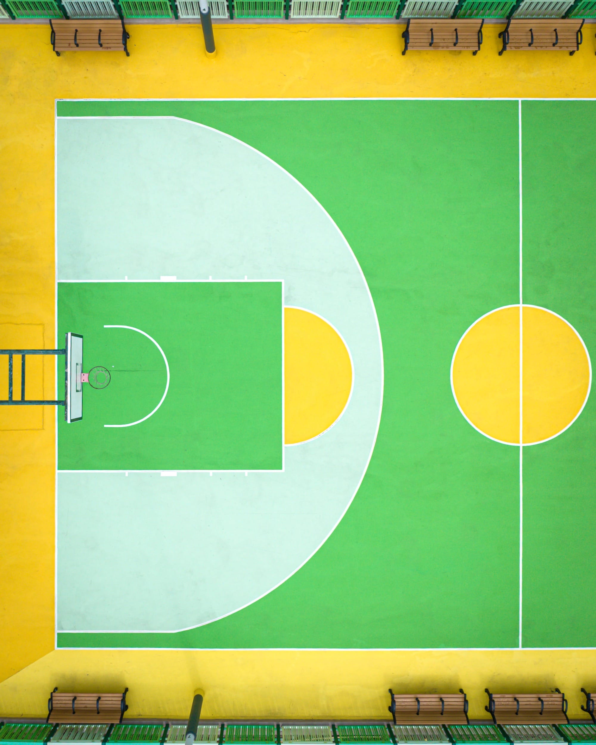 A detail of a colorful green-and-yellow basketball court
