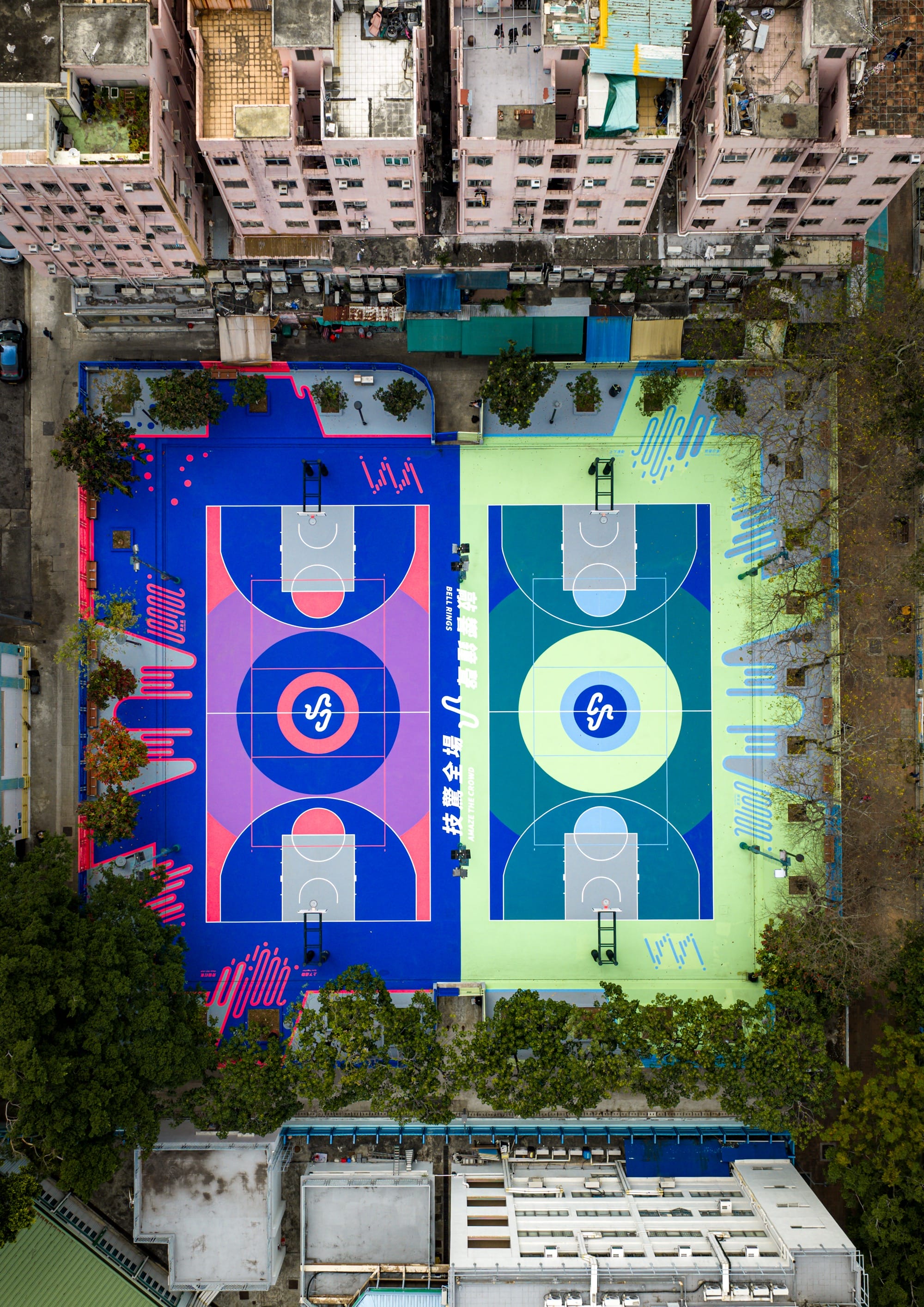 An aerial view of two colorful basketball courts amid tall buildings in Hong Kong