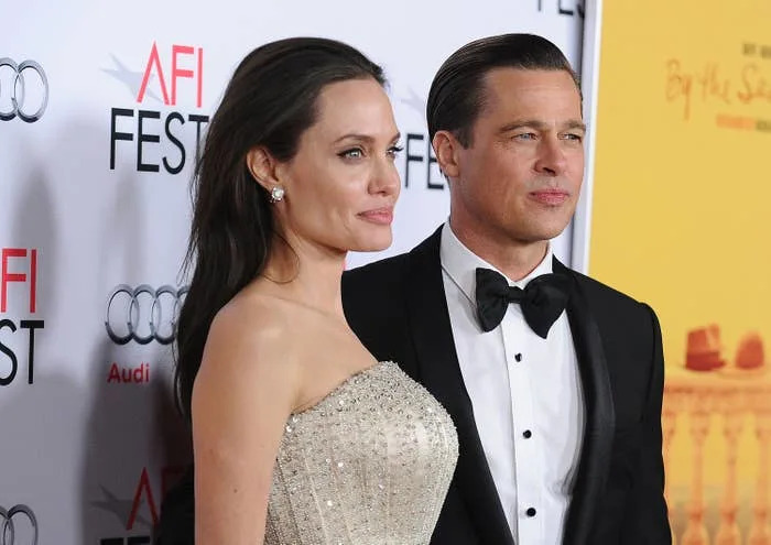 A woman in an elegant strapless gown and a man in a classic tuxedo pose on a red carpet at a film festival event