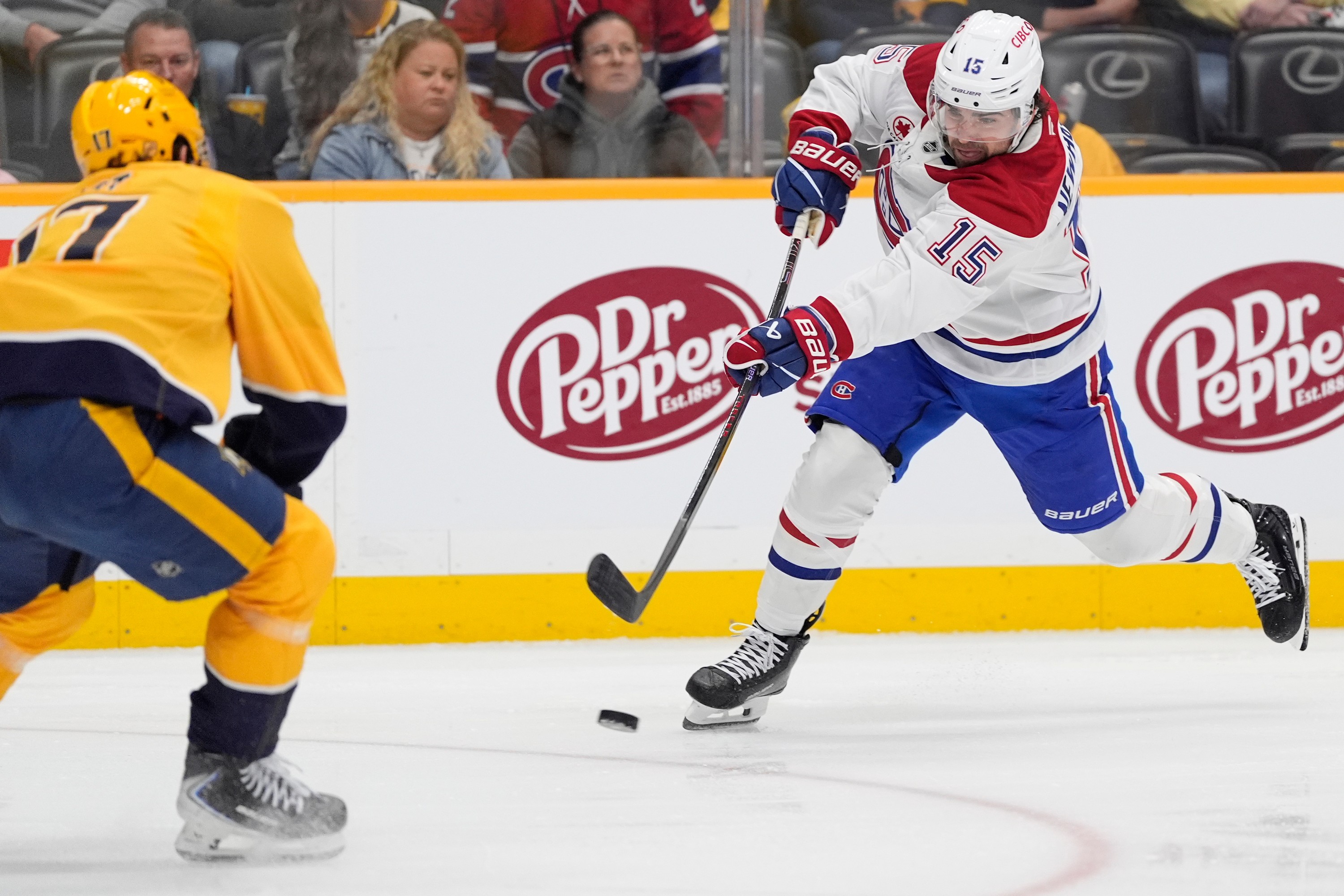 Hockey player shoots the puck past a defender.