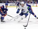 Vancouver Canucks right wing Brock Boeser battles for a loose puck with New York Islanders defenceman Alexander Romanov in 2024.