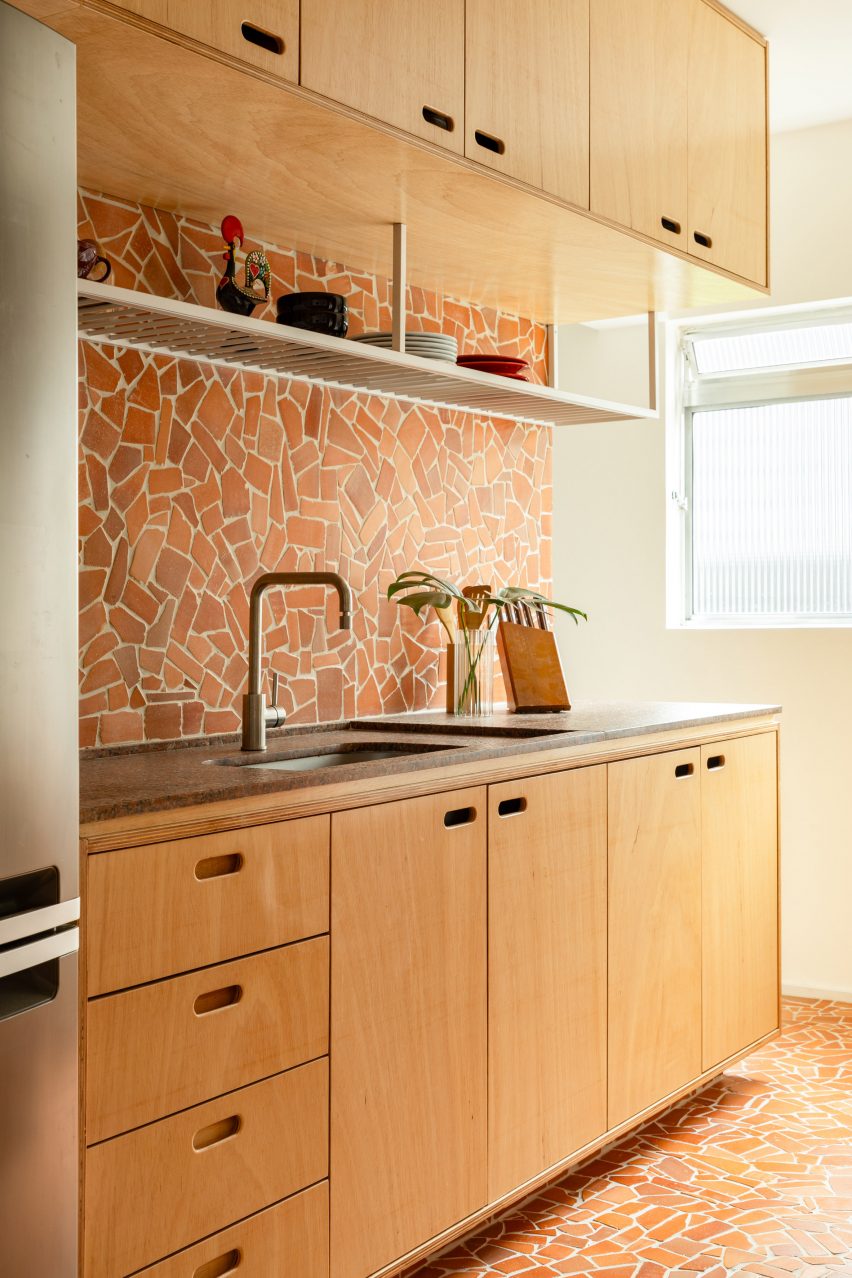 Irregularly shaped fragments of caquinhos tiles laid to create kitchen flooring and backsplash