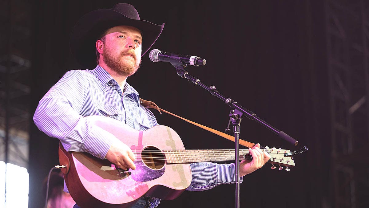 Colter Wall singing and playing guitar onstage during a music festival.