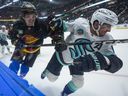 Vancouver Canucks' Curtis Douglas, left, checks Seattle Kraken's Matty Beniers.