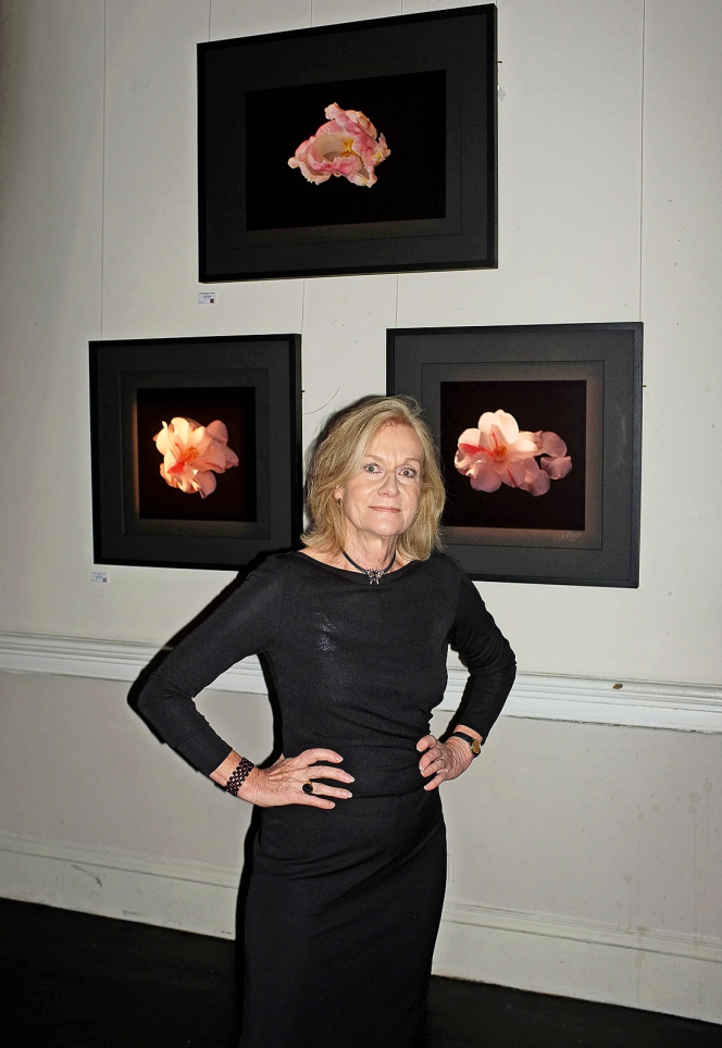 Photographer Carole Latimer standing in front of her "Flowers, Mirroring The Deep" exhibition.