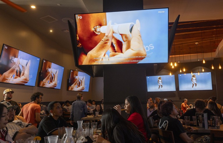 A commercial for GLP-1 drugs during the Super Bowl LX broadcast on television screens at a bar in Los Angeles, California.