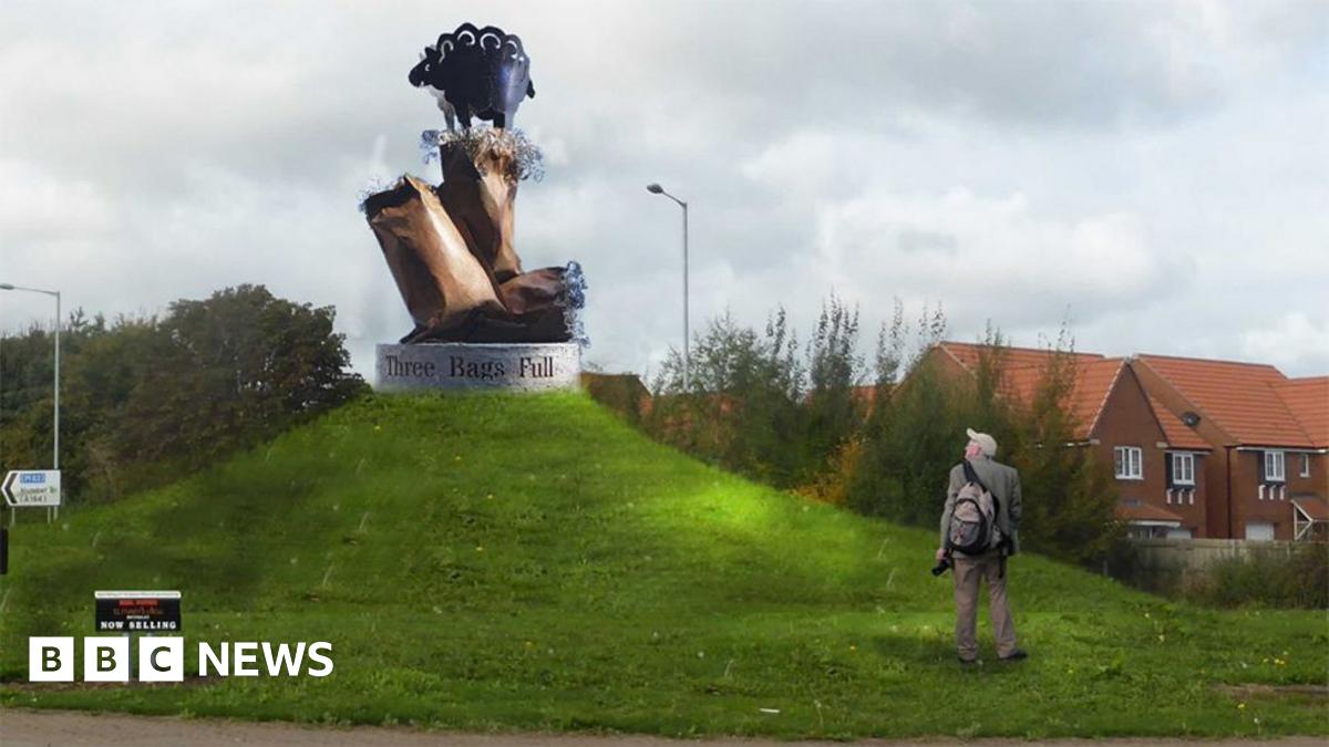 An artist's impression of the sculpture on a plinth with the words "Three Bags Full" on the side. It is on a grass mound. The bronze bags have wool sticking out of them. The black metal sheep is standing on the top bag.