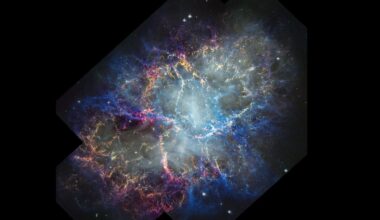 A glowing nebula of pink, blue and orange is seen in the darkness of space