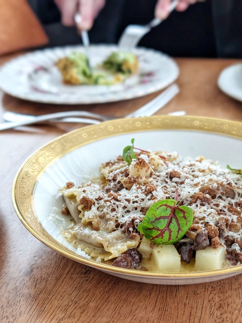Charred cabbage agnolotti at Deane House in Calgary in a bowl with potatoes, mushrooms, rye breadcrumbs, and Avonlea clothbound cheddar