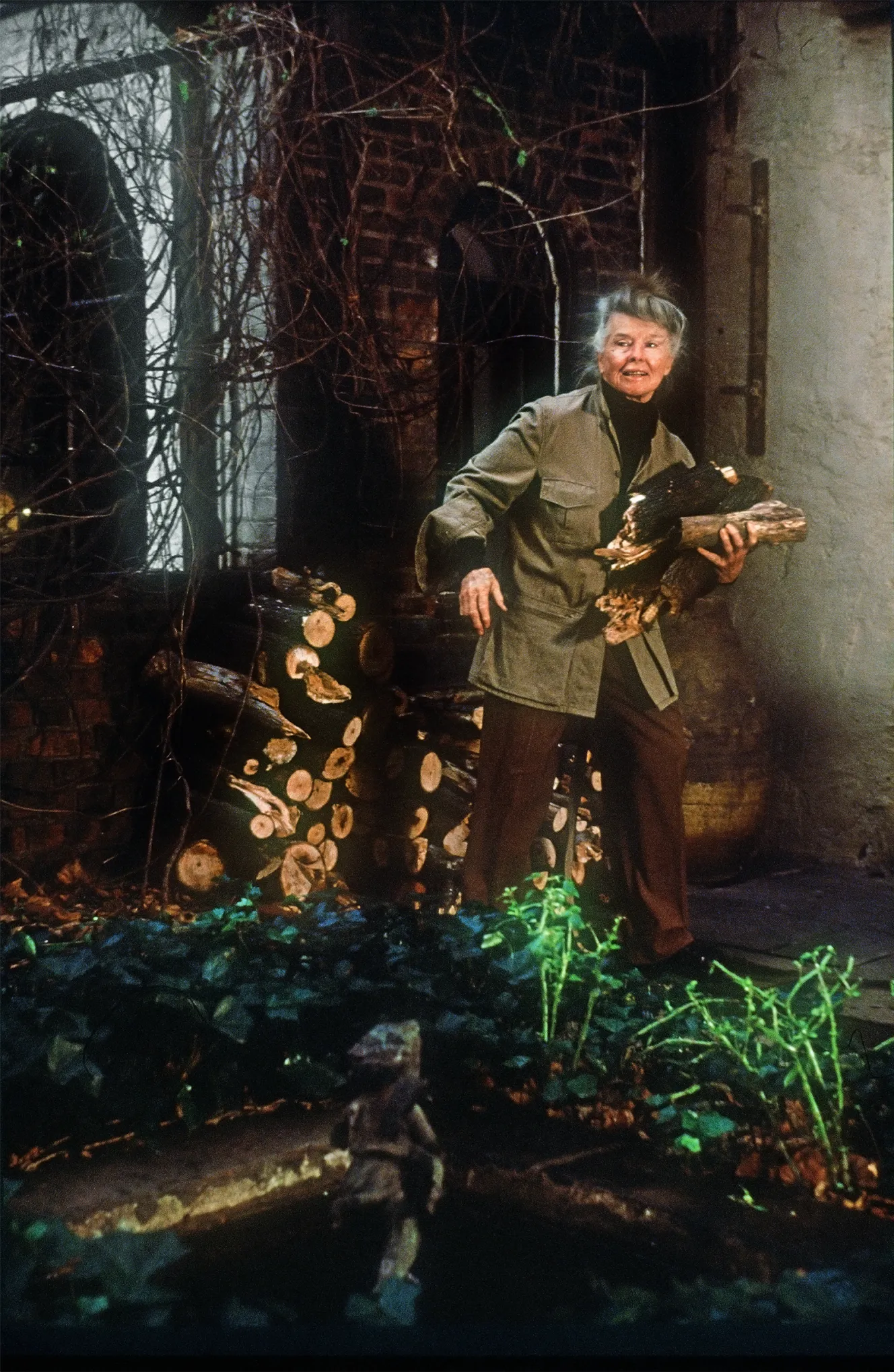 Katharine Hepburn carrying firewood outside.