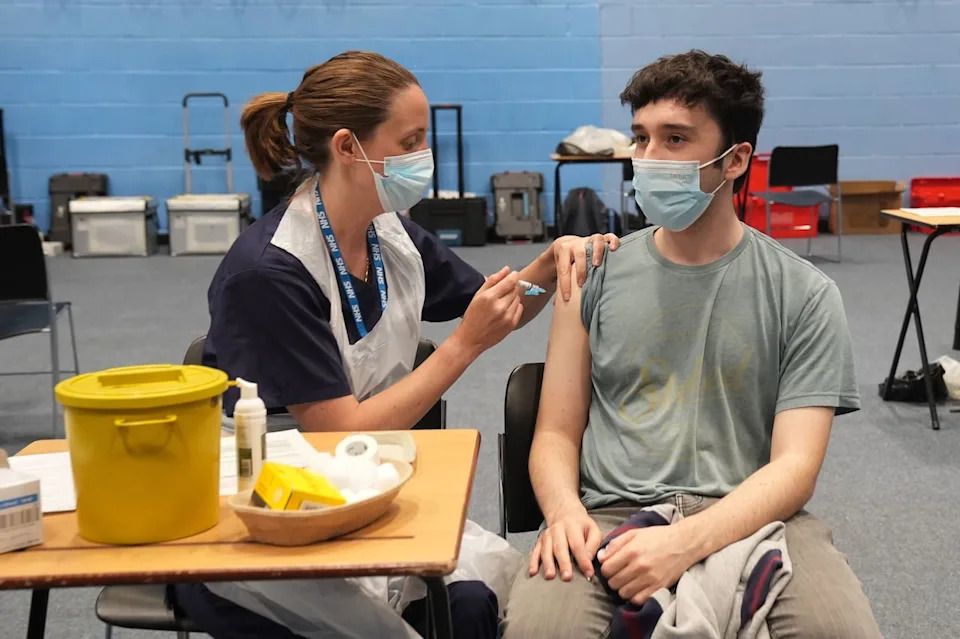 22-year-old postgraduate law student Oliver Contreras, right, receives an injection in the sports hall at the University of Kent campus in Canterbury, England, Wednesday, March 18, 2026, where the rollout of a meningitis B vaccine to about 5,000 students has begun.  (Gareth Fuller/PA via AP)