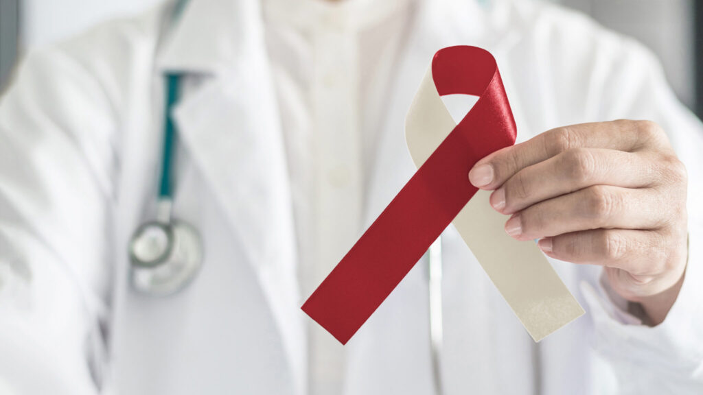 Burgundy ivory ribbon awareness on doctor's hand, symbolic bow color for head and neck cancer, oral squamous cell carcinoma, throat, laryngeal and pharyngeal cancer. (iStock)