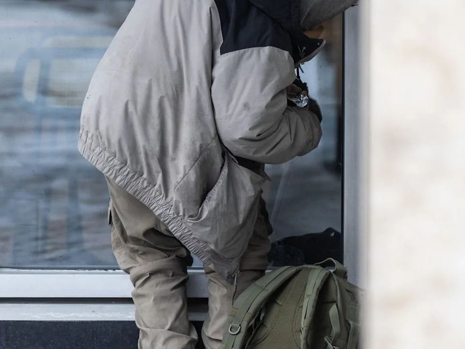  A man huddles in a corner to smoke drugs outside of the drug site at the Sheldon M. Chumir Health Centre in Calgary on December 12, 2025.