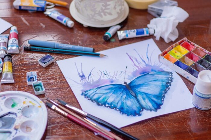 elena-mozhvilo-art-butterfly-unsplash - Ottawa Road Trips half-finished watercolour painting of a butterfly, surrounded by artists' materials