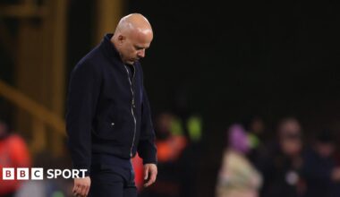 Rob Edwards raises his fists to the air and shouts in celebration, eyes closed