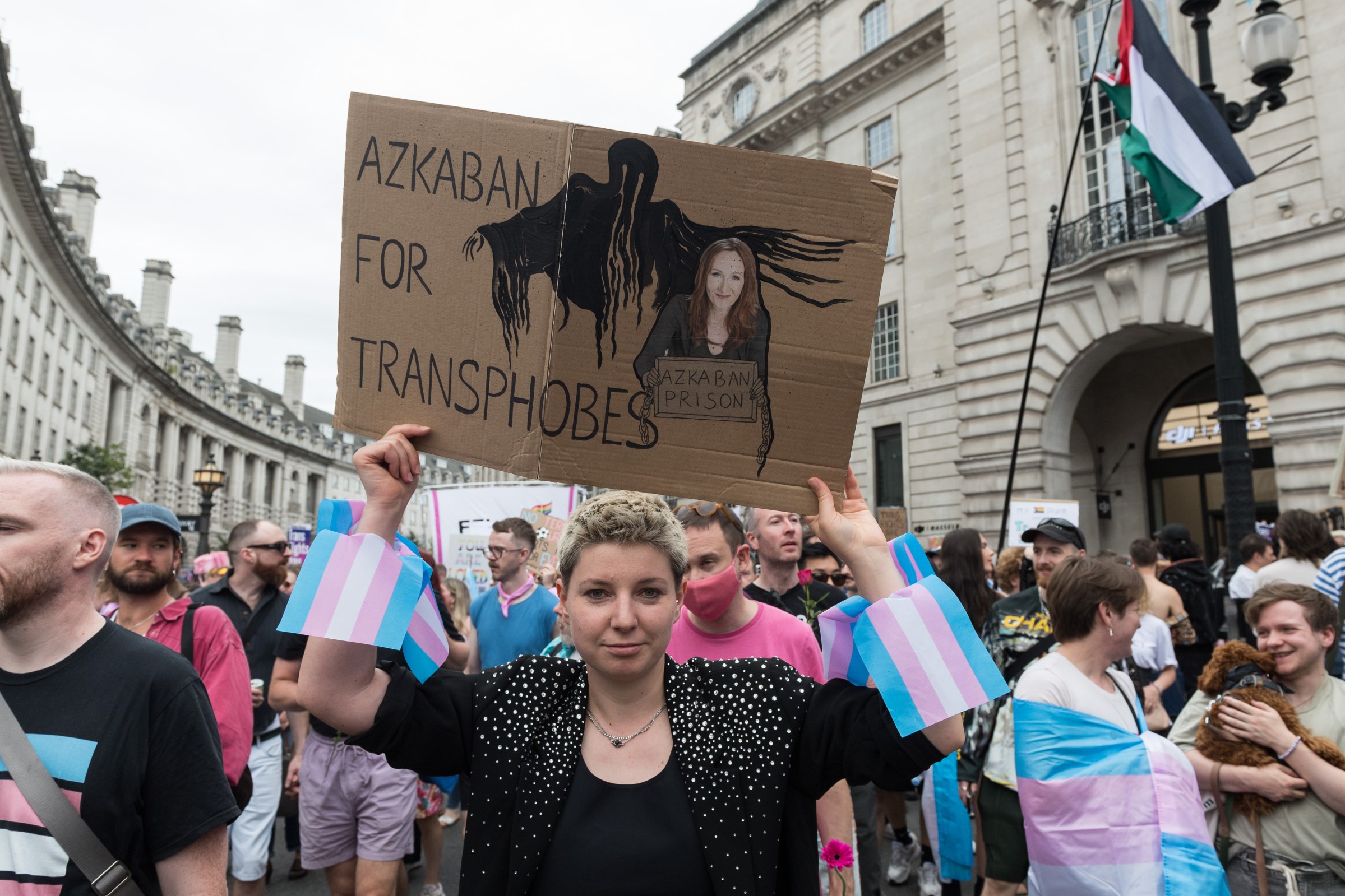 A person holding up a cardboard sign depicting author JK Rowling and a shadowy hooded figure. The sign reads: Azkaban for transphobes.