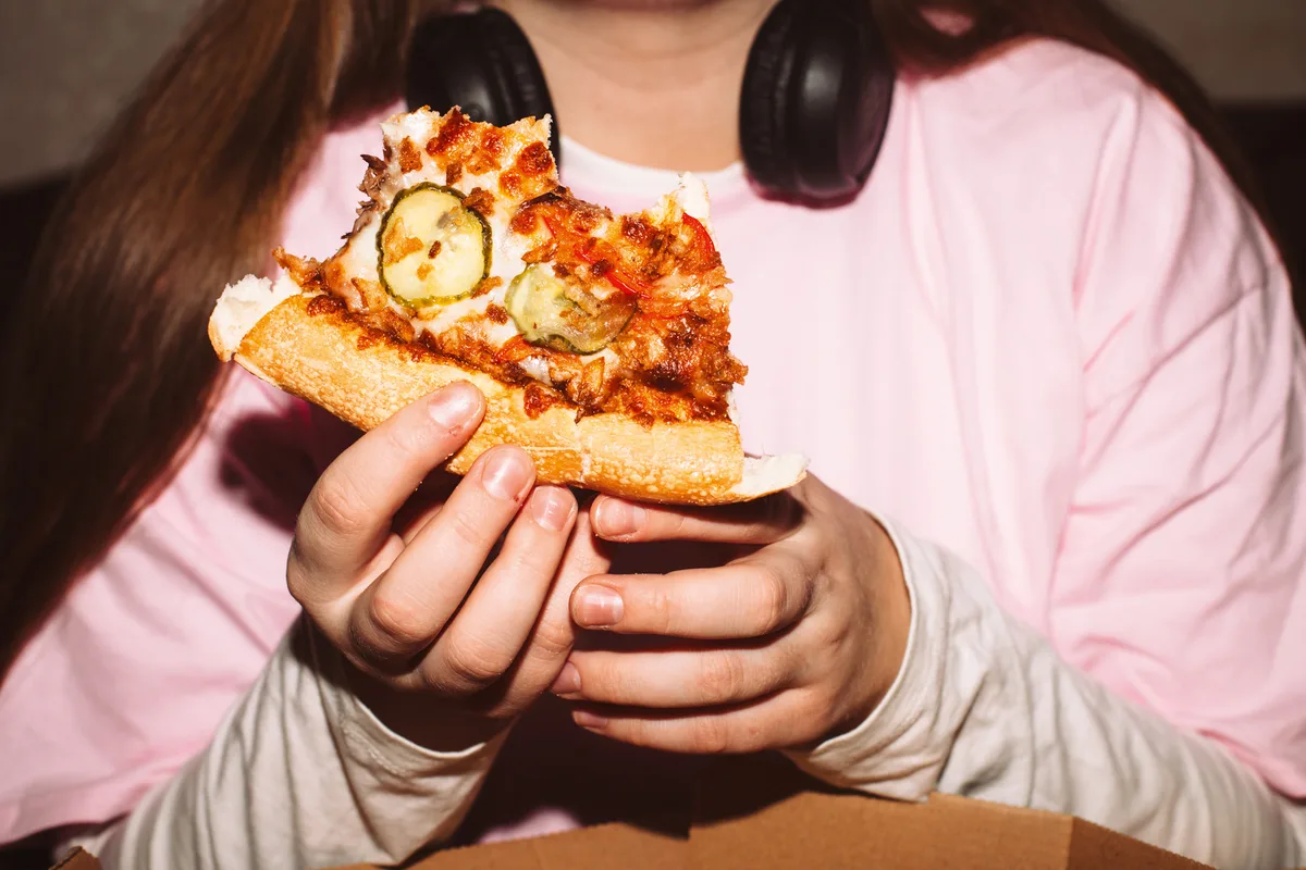 Young woman eating pizza at house party