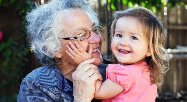 Older woman hugging a young child while they both smile