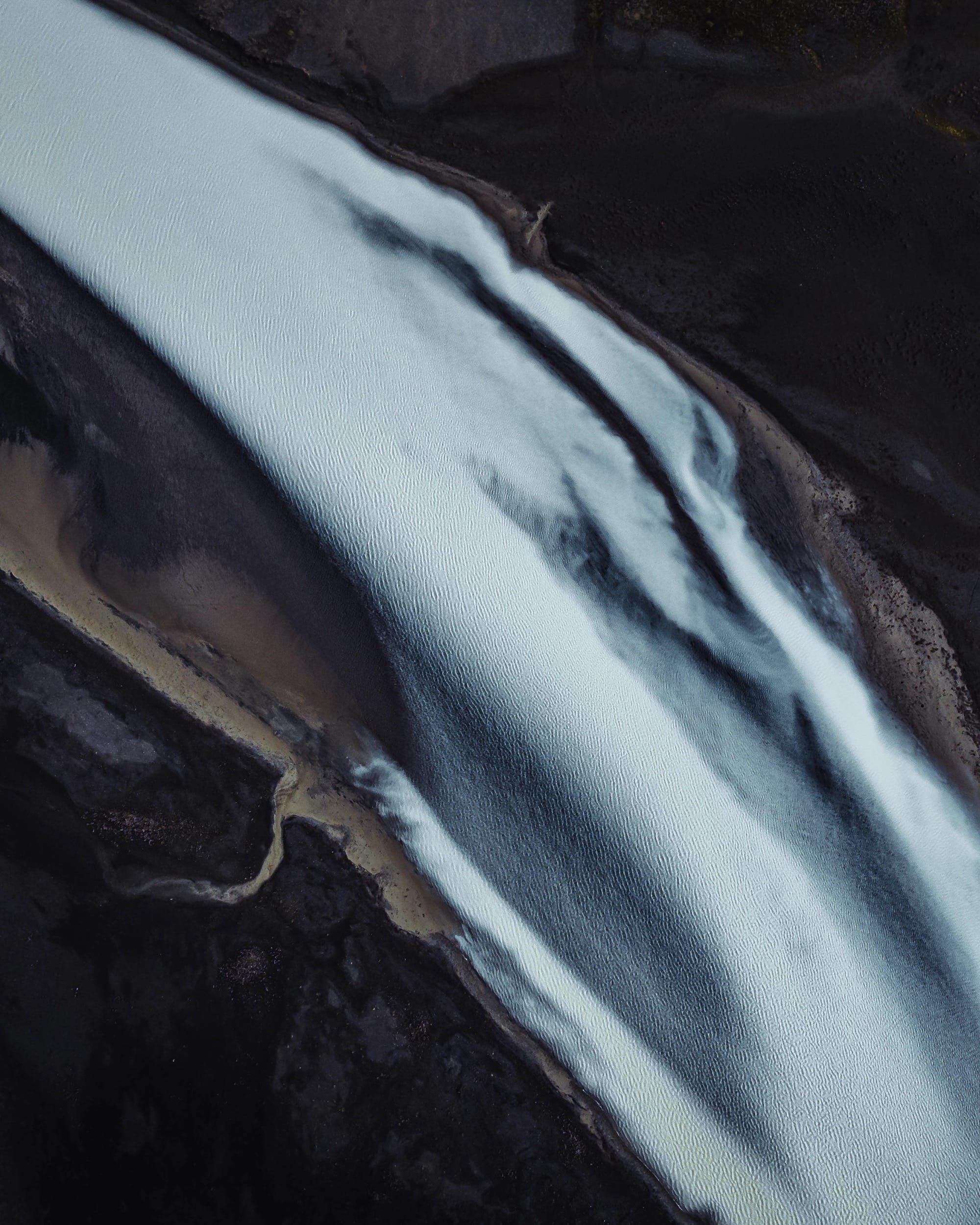 An abstract aerial view of silty water floating in a glacial stream in Iceland