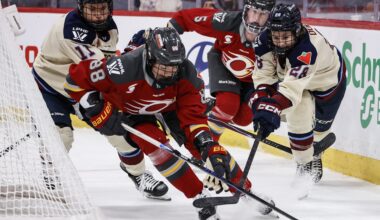 Hockey player races after an opponent behind the net.