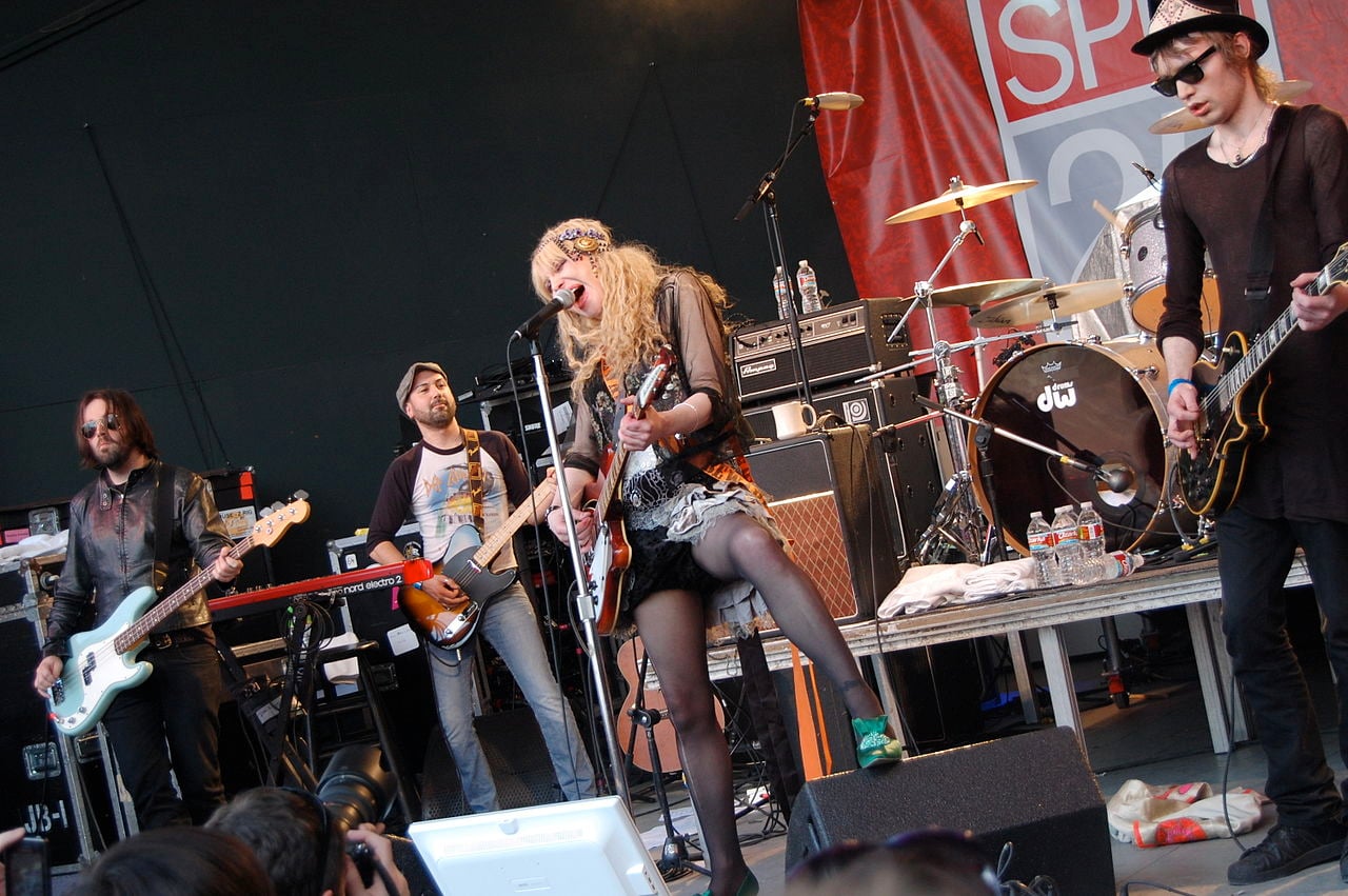 HOLE performing on stage during their SXSW 2010 concert in Austin, Texas, with band members playing guitars and drums under stage lights.
