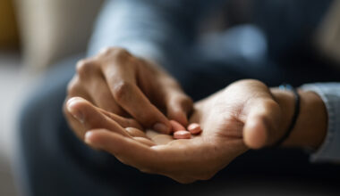 Closeup Shot Of Black Man Holding Few Pills In Hand While Sitting On Couch At Home, Unrecognizable African American Male Taking Supplement Vitamin Or Painkillers, Having Medical Treatment, Cropped