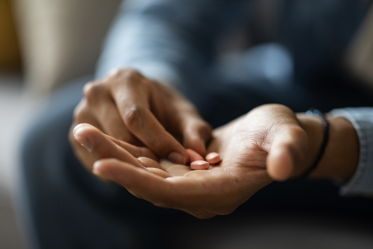 Closeup Shot Of Black Man Holding Few Pills In Hand While Sitting On Couch At Home, Unrecognizable African American Male Taking Supplement Vitamin Or Painkillers, Having Medical Treatment, Cropped