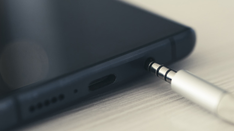 A 3.5mm audio connector being plugged into a smartphone