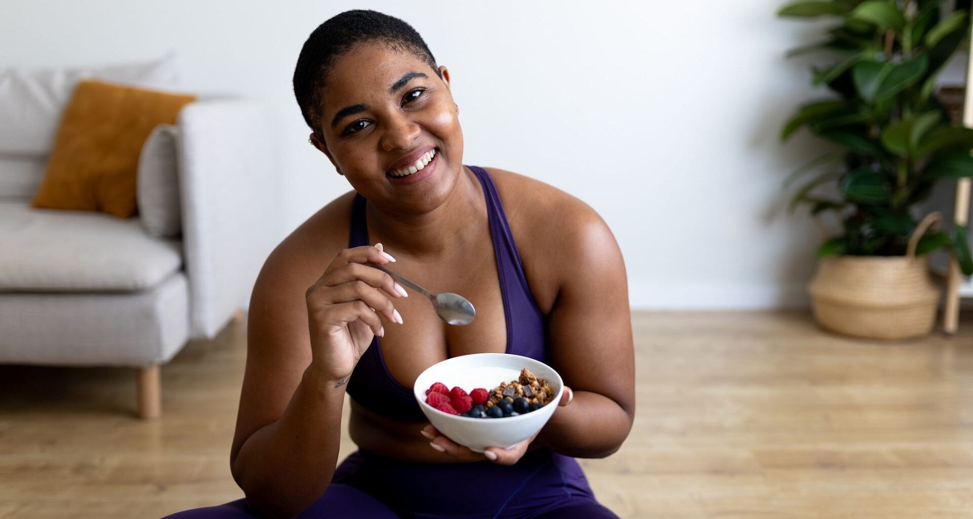 woman eats a bowl of yoghurt and fruit post workout