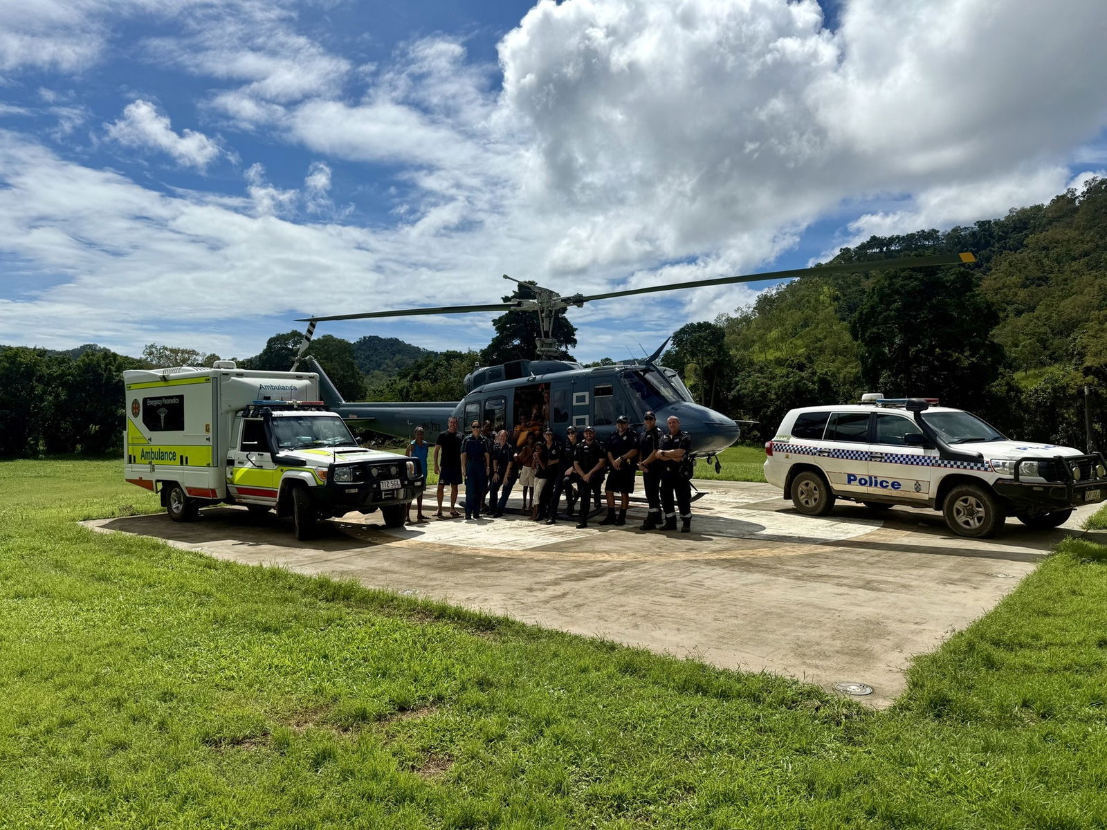 An ambulance and police car next to a helicopter on a landing pad. 