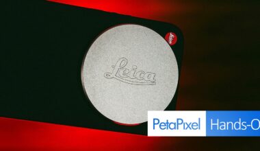 Close-up of a Leica camera lens cap with the Leica logo embossed on it, set against a dark background with a red glow. A "PetaPixel Hands-On" label appears at the bottom right corner.