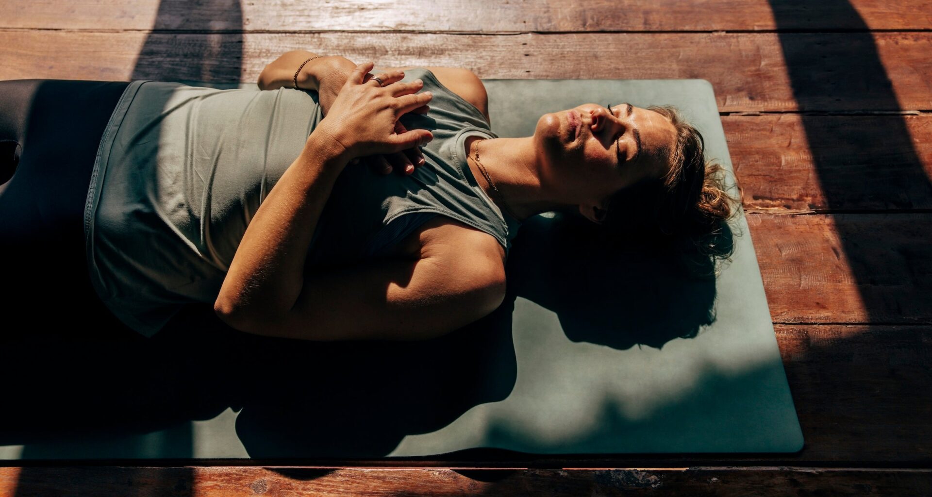 woman lies on yoga mat in the sun preparing for sleep, representing one of the top 2026 health and wellness trends
