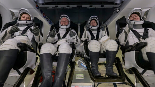 Four NASA astronauts sitting in a spacecraft 