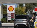 The price per gallon of gas is shown on a sign as a customer gets fuel at a station on March 9, 2026, in Miami, Fla.