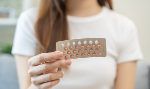 A hand holding a pack of birth control pills.