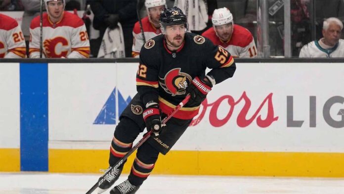 Ottawa Senators #52 MacKenzie Weegar skating with the puck on ice.