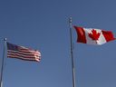 Canadian and American flags blow in the wind.