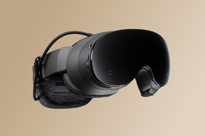 The Steam Frame virtual reality headset viewed at an angle against a light-brown backdrop.