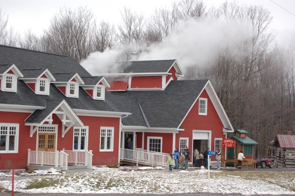 small TEMPLE'S MAPLE SUGAR CAMP AND RESTAURANT - Ottawa Road Trips red building with dormer windows, surrounded by trees.