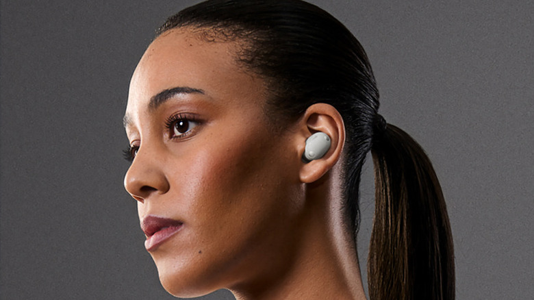 A woman wearing the Sony WF-1000XM6 earbuds in front of a gray background