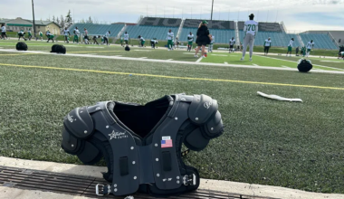 The Riders on the field as a set of shoulder pads sits on the sideline at Griffiths Stadium in Saskatoon.