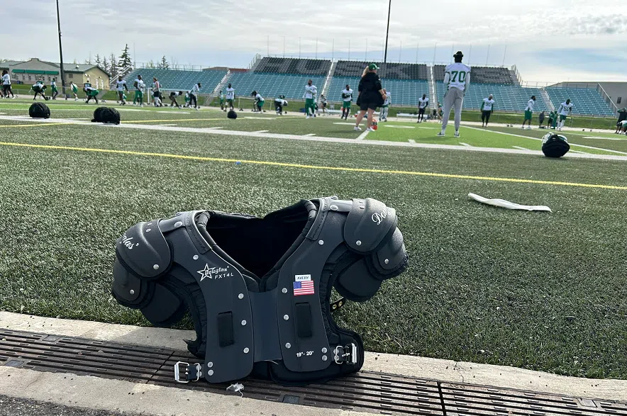 The Riders on the field as a set of shoulder pads sits on the sideline at Griffiths Stadium in Saskatoon.