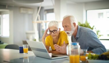 Two people with concerned expressions looking at a laptop.